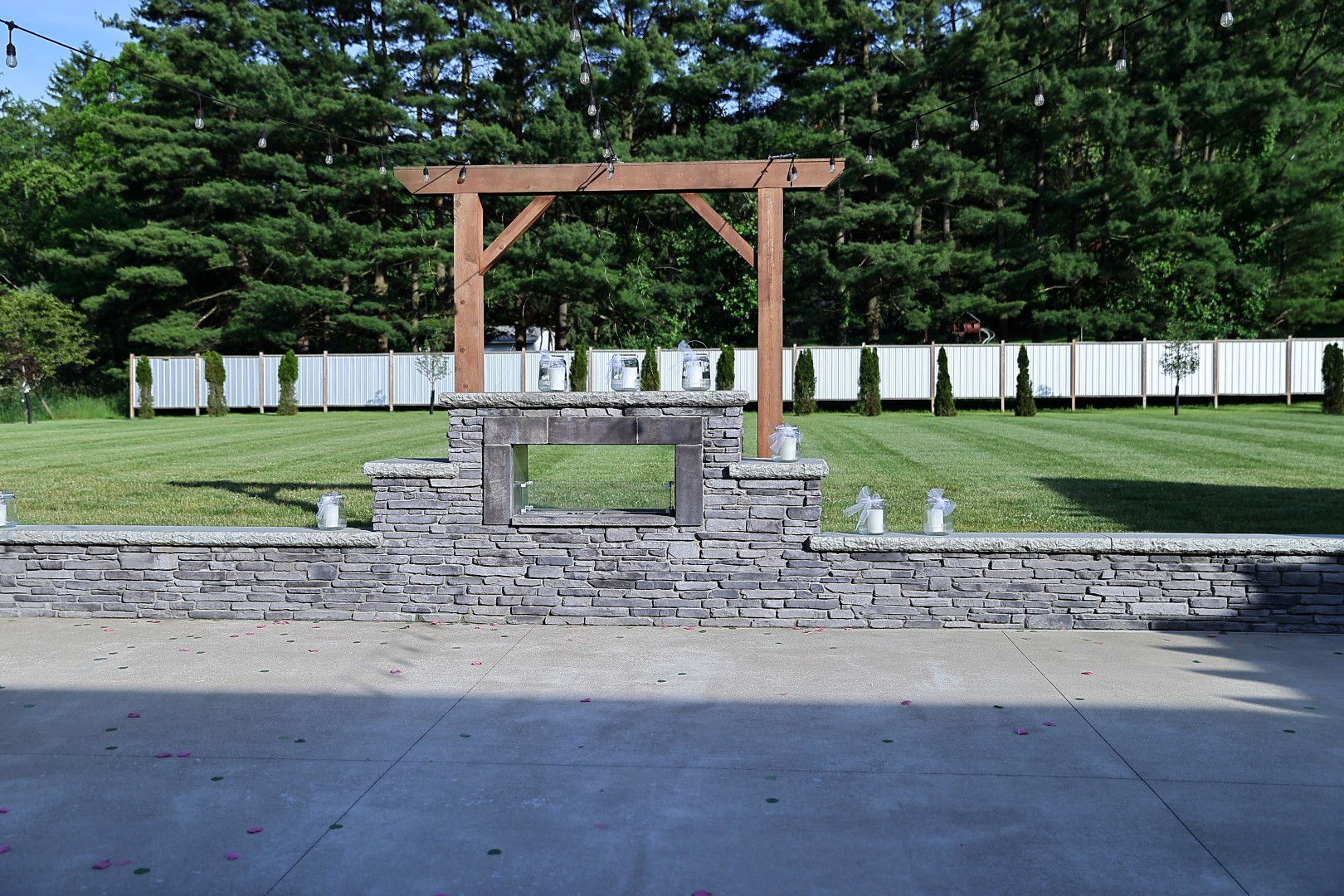 Patio and cedar pergola Stone fireplace wall and cedar pergola strung with bistro lights overlooking the lawn