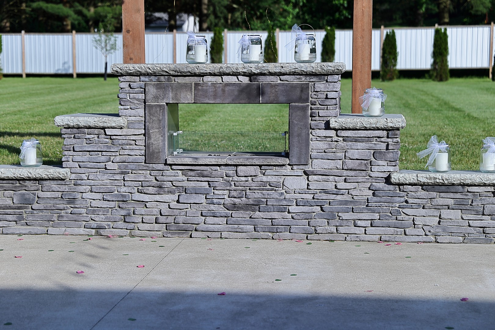 Stone outdoor fireplace Stacked stone outdoor fireplace lined with candle lanterns and scattered rose petals