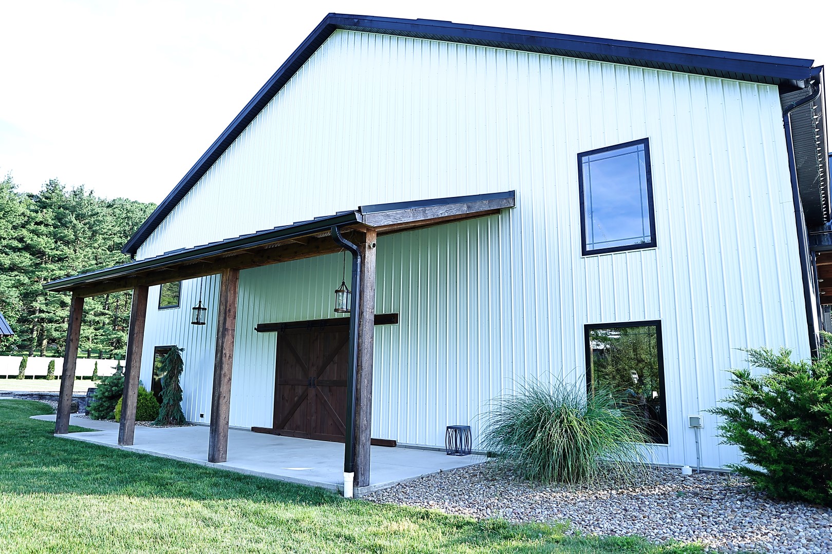 Daytime view of the white barn exterior with a covered timber porch and sliding barn door
