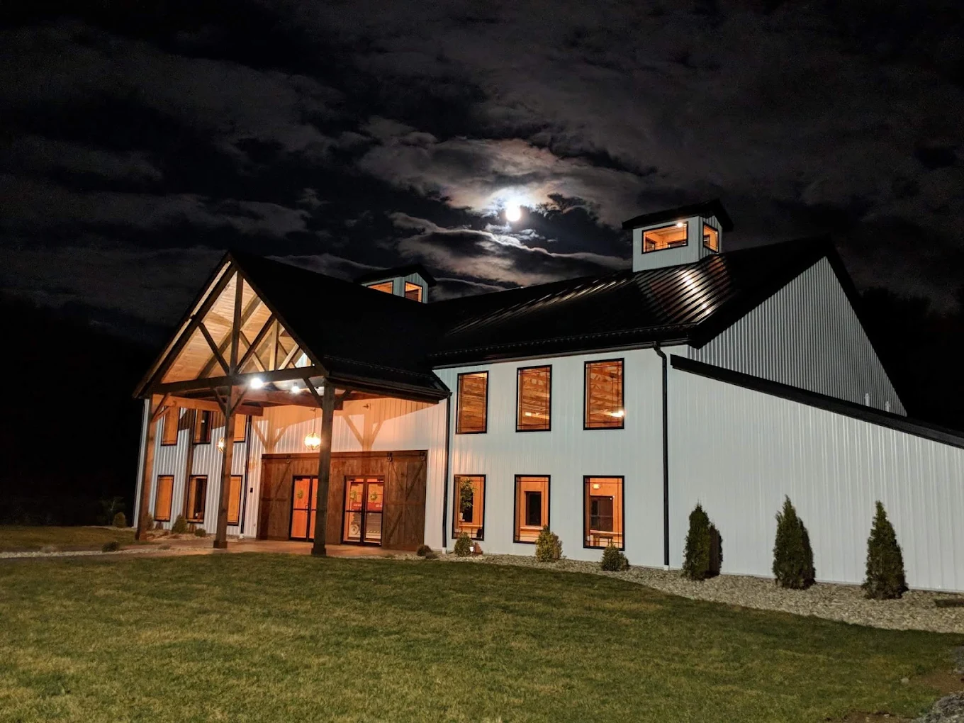 Rustic Ridge Wedding Barn exterior lit up at night under a full moon