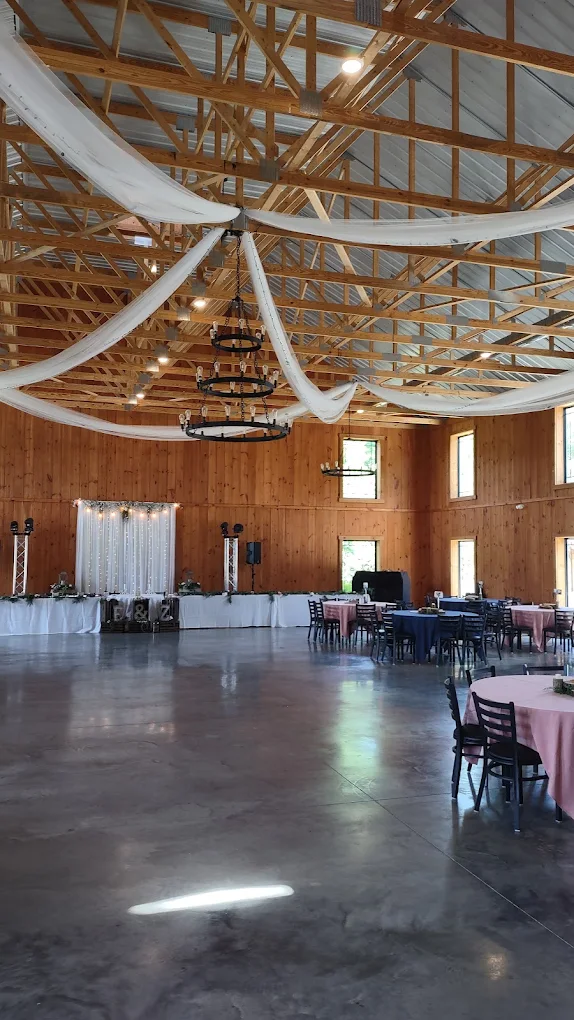 Head table with white draping and string lights inside the Rustic Ridge barn
